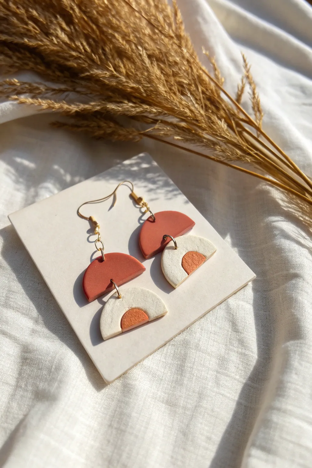 Modern mini clay arch earrings in bold two-tone style on linen, minimalist and handmade.