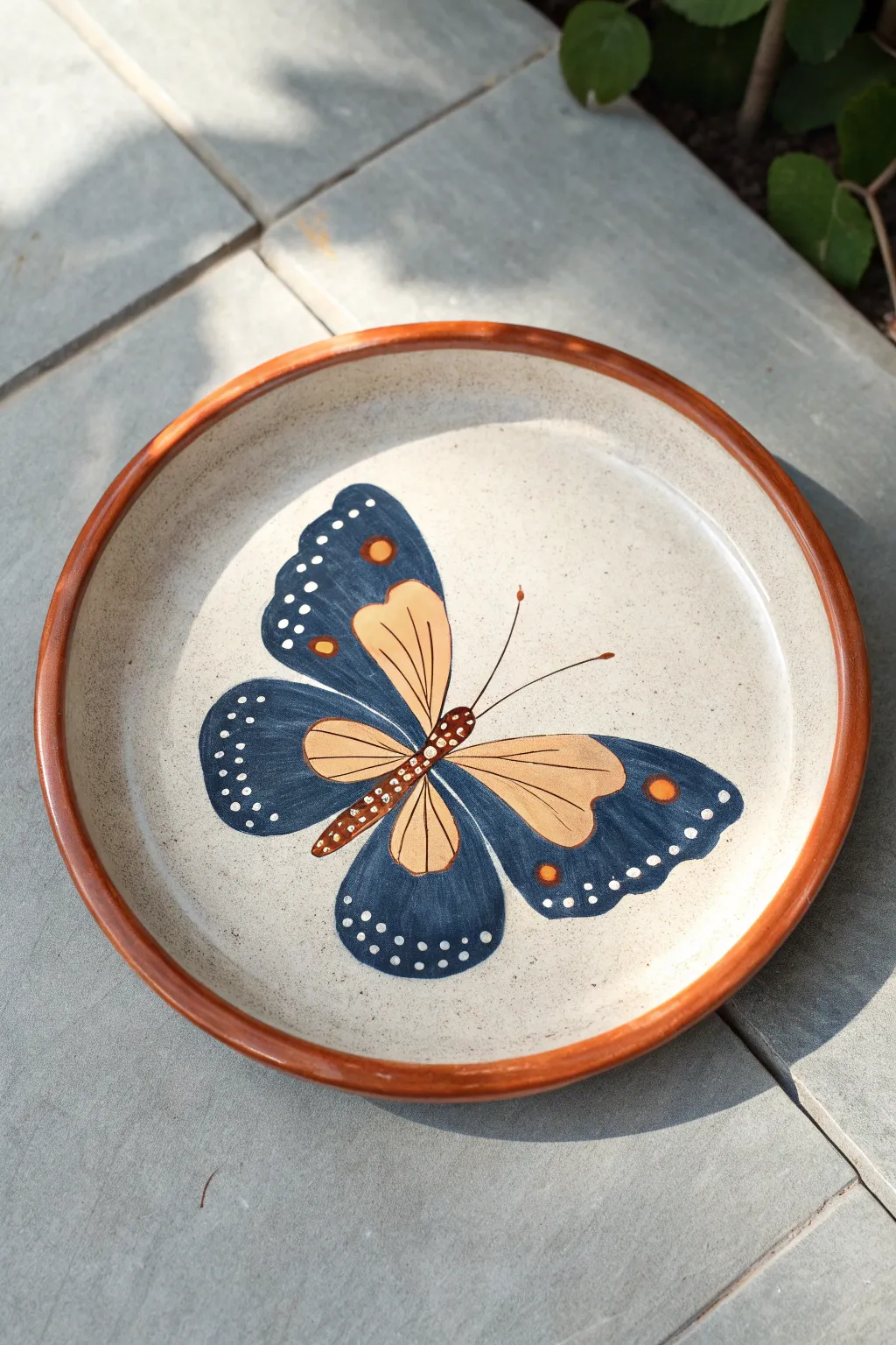 Minimalist plate painting: a single bold butterfly centerpiece with a thin rim border line.