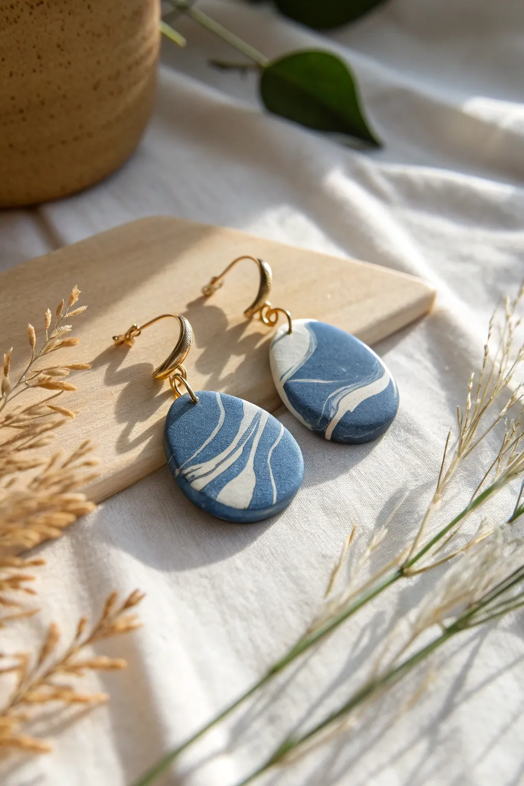 Organic pebble-shaped polymer clay earrings in bold color, minimal flat lay, calm Nordic vibe.