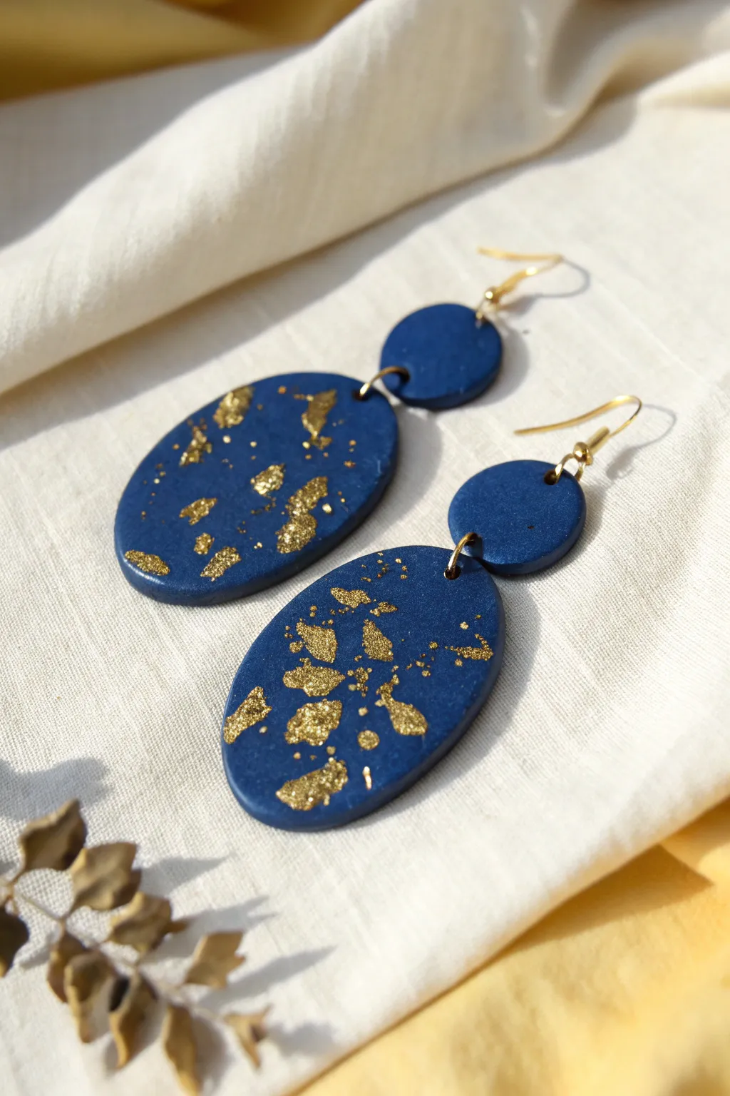 Minimal oval polymer clay earrings with scattered gold leaf flakes, bold yet beautifully simple.