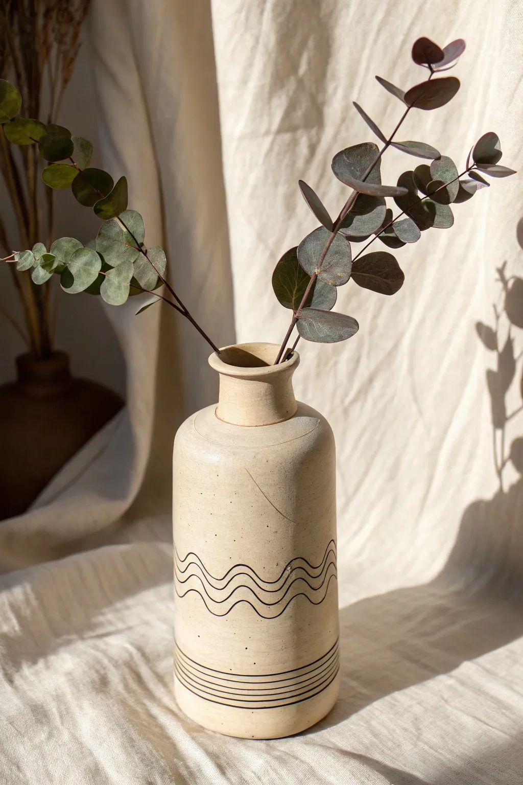 Cream polymer clay vase with minimalist line-face relief, styled with a single stem in soft light.