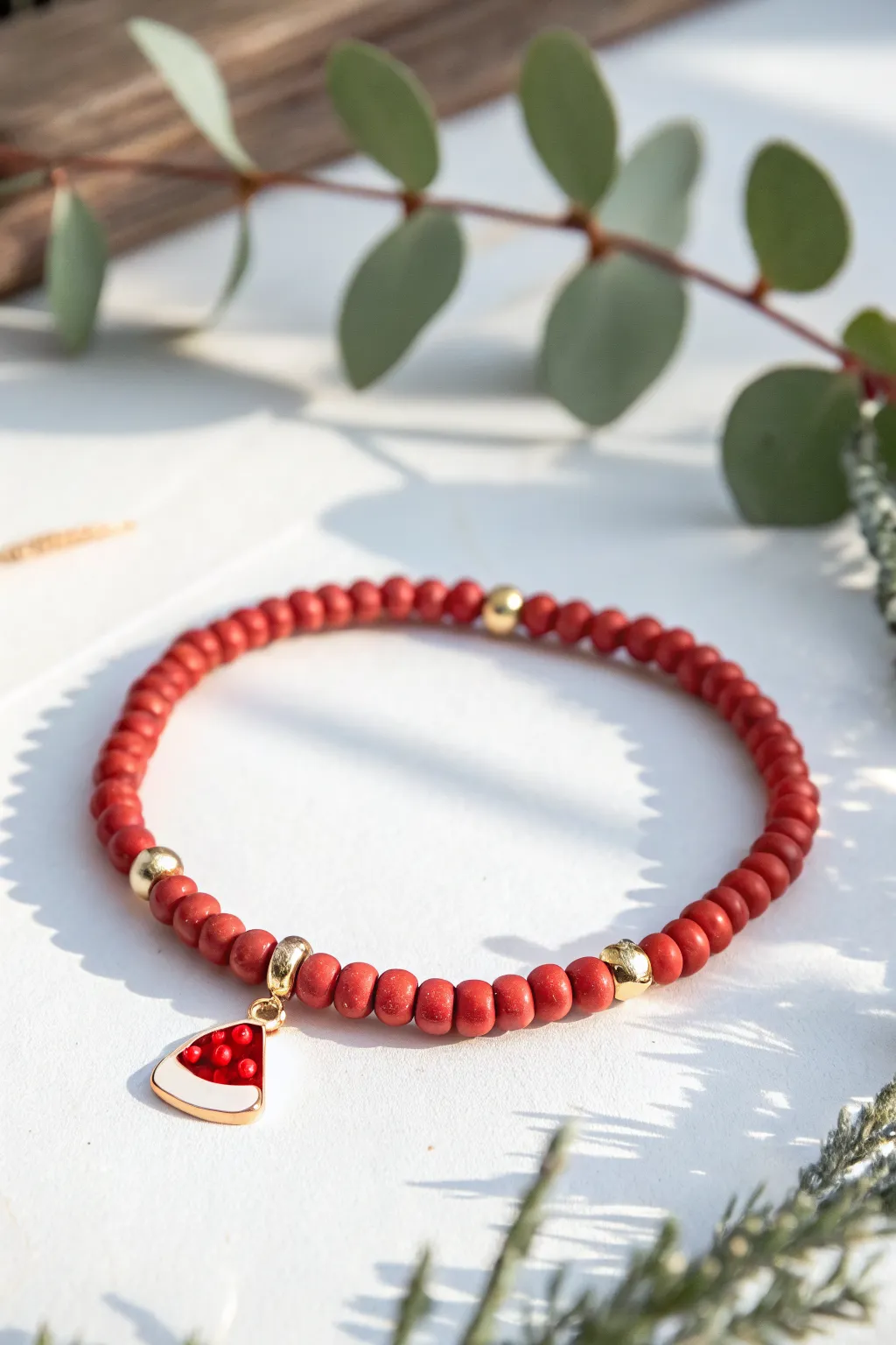 Preppy holiday pop: a bold red heishi bracelet with a sweet Santa hat charm and gold spacers.