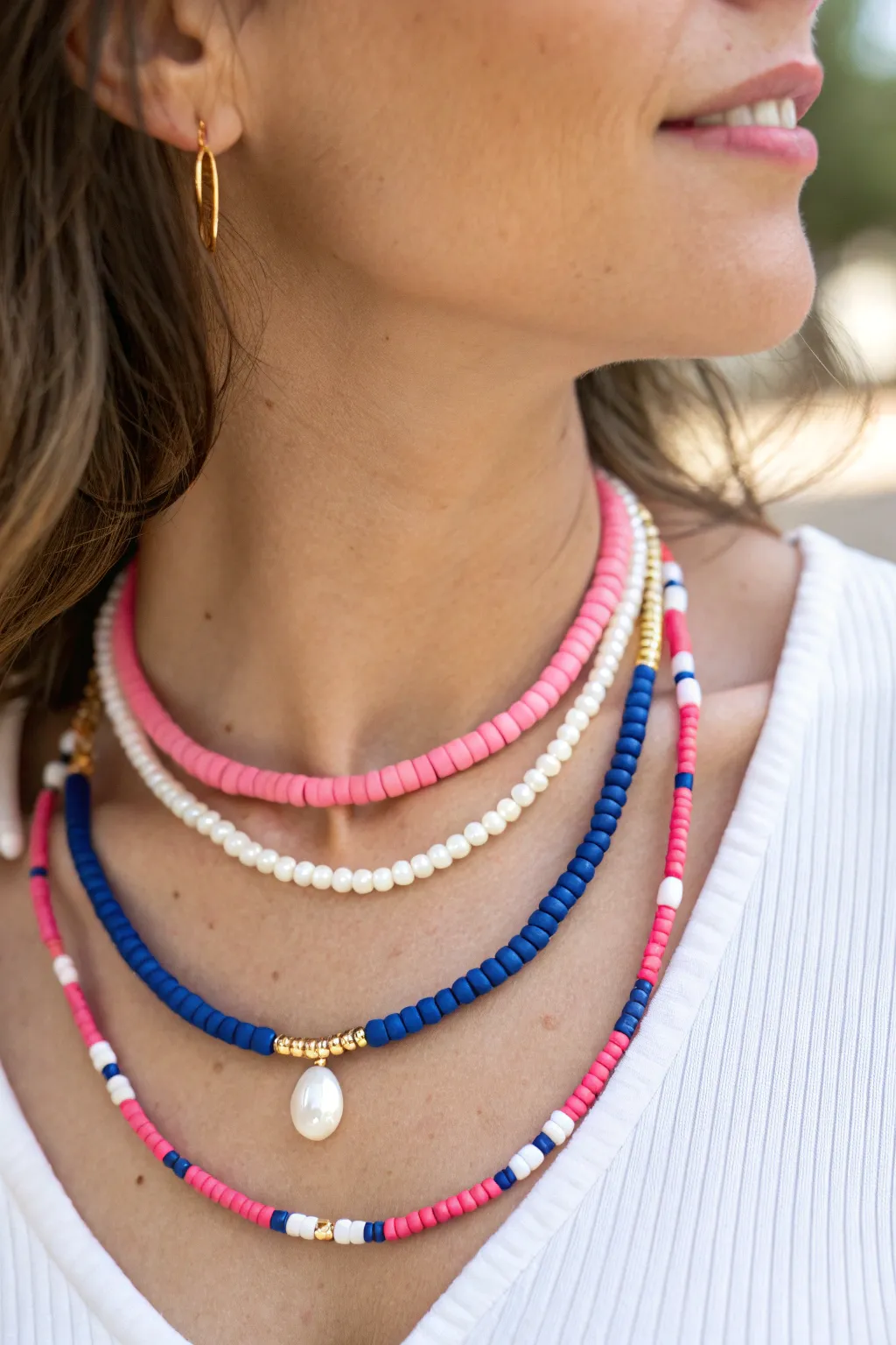 Layered preppy necklace stack with heishi, pearl-accent clay beads, and a simple gold chain