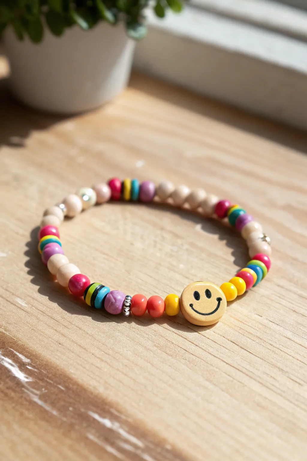 Rainbow heishi bracelet with a bold smiley centerpiece, minimalist styling and vibrant color contrast