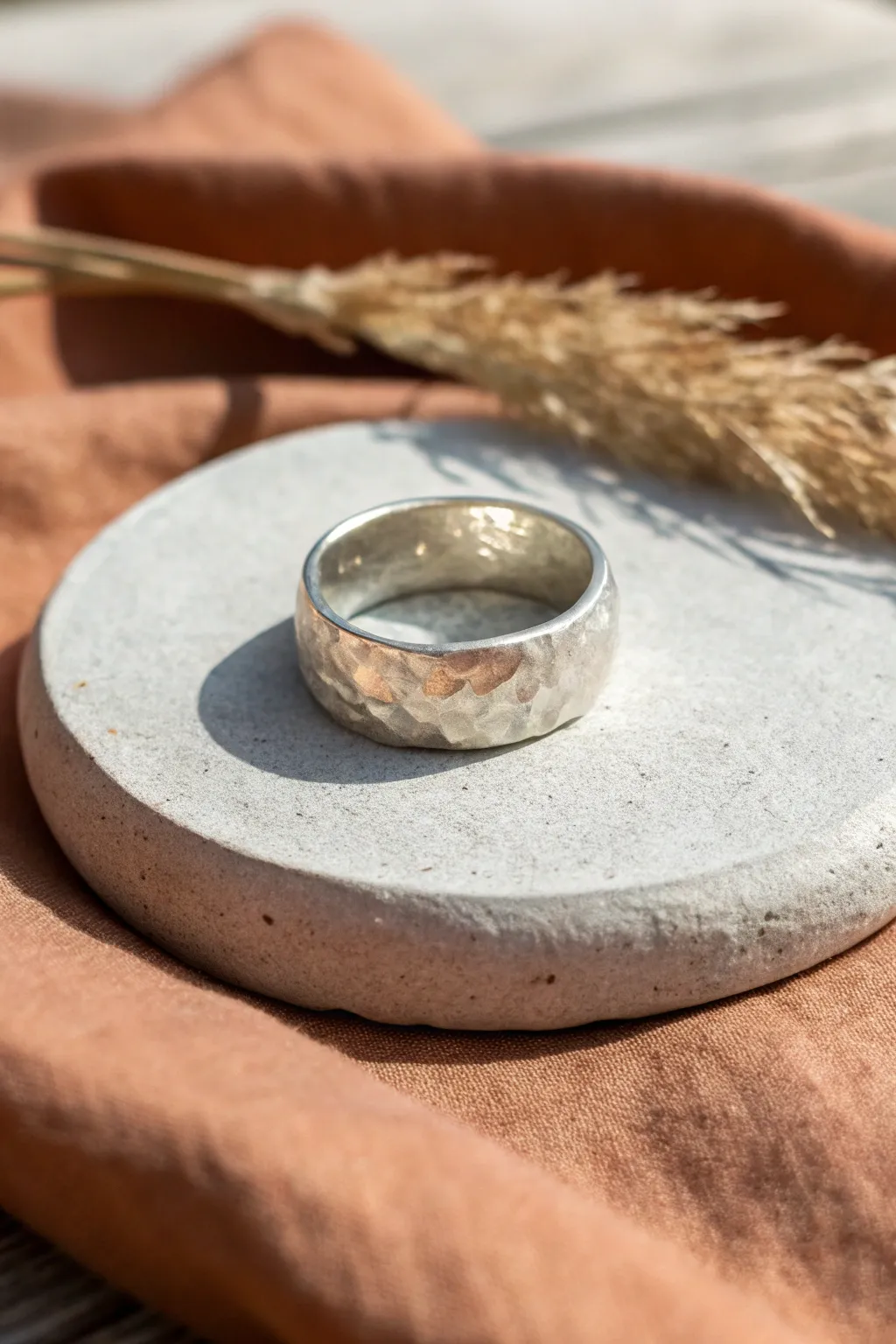 Soft hammered silver clay ring on matte concrete, minimalist styling with warm boho tones.