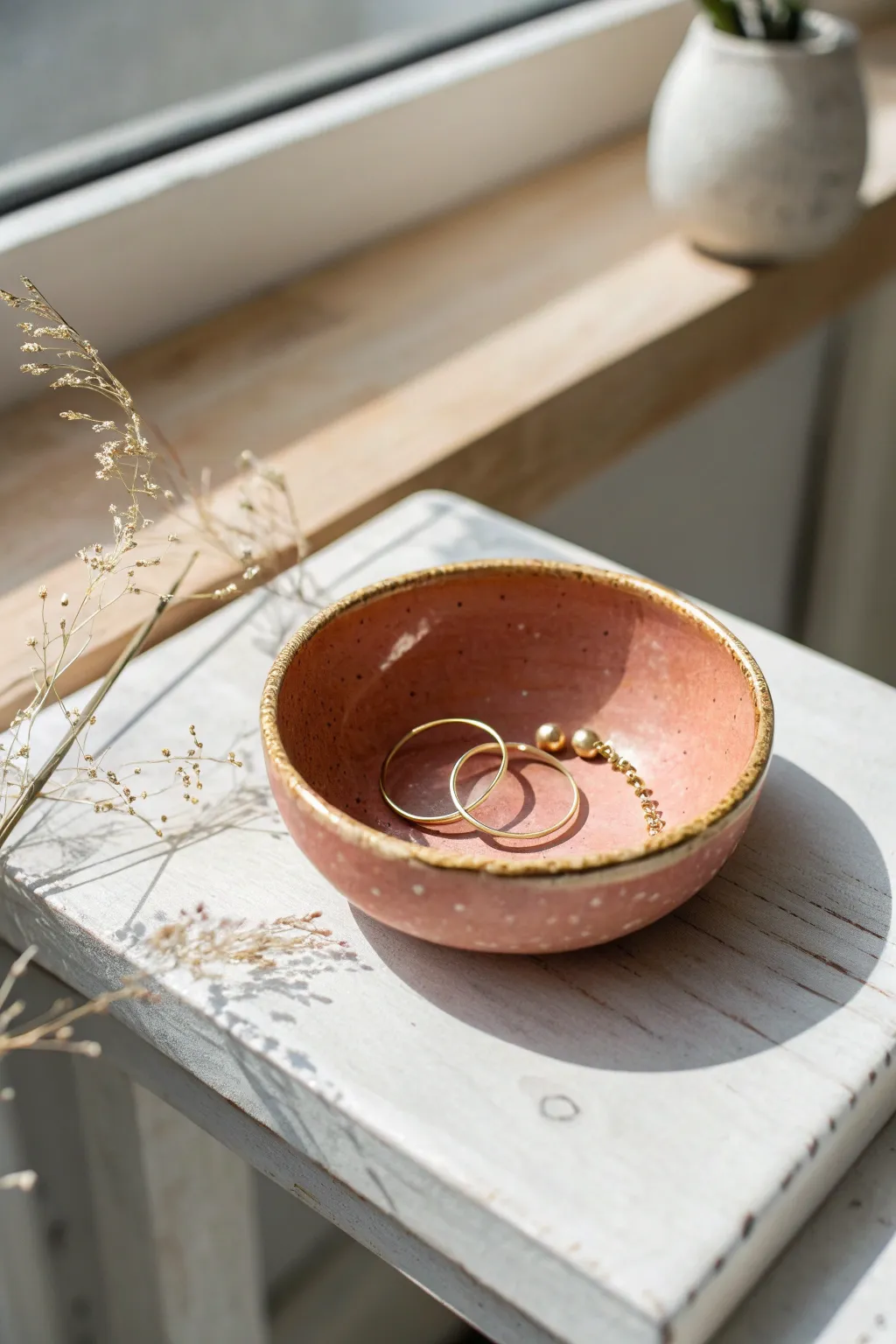 Minimal trinket bowl with a gold rim, holding a bracelet—simple clay elegance for your vanity.