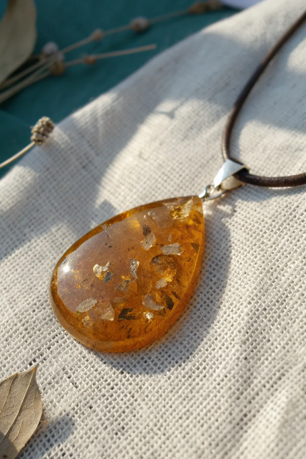 Honey amber translucent pendant with floating gold flakes, glowing in warm Scandinavian light.