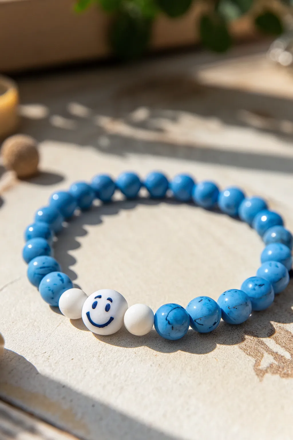 Mostly blue clay bead bracelet with white smiley focal beads, sunlit and minimal.