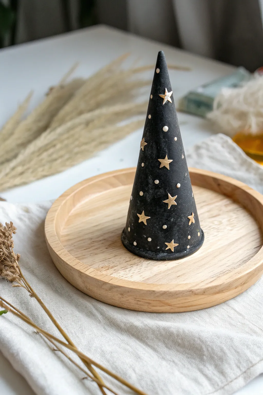 Minimalist Halloween ring holder: matte black air-dry clay witch hat with tiny star details.