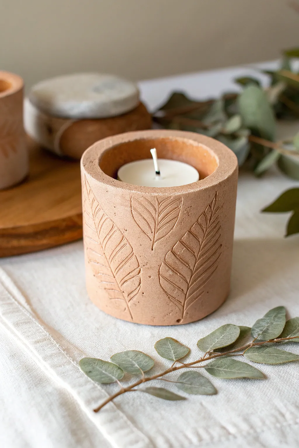 Botanical leaf-imprint tea light holder in earthy tones, styled with simple natural leaves