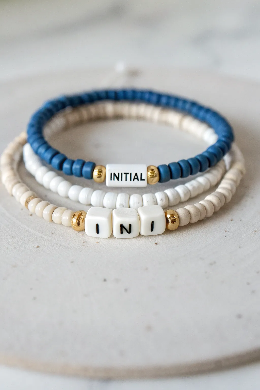 Blue-white heishi bracelet with a single initial centerpiece, minimal and handmade for summer styling.