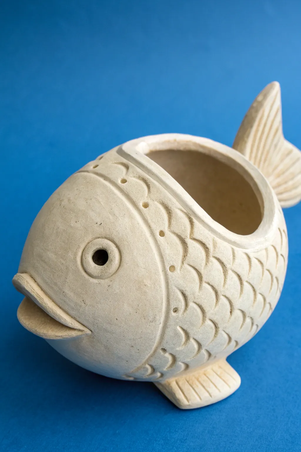 Chunky double-pinch pot fish with stamped scales on bold blue, minimal and craft-forward.