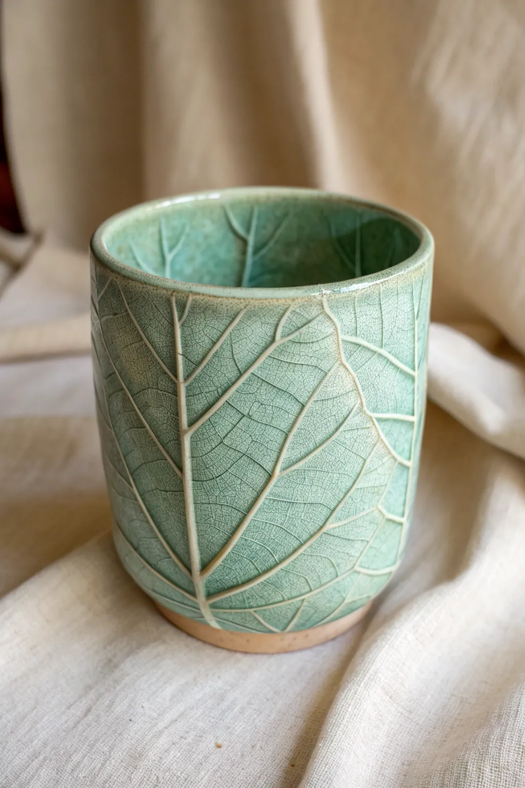 Leaf-vein imprinted clay cup with a translucent glaze that highlights every natural line