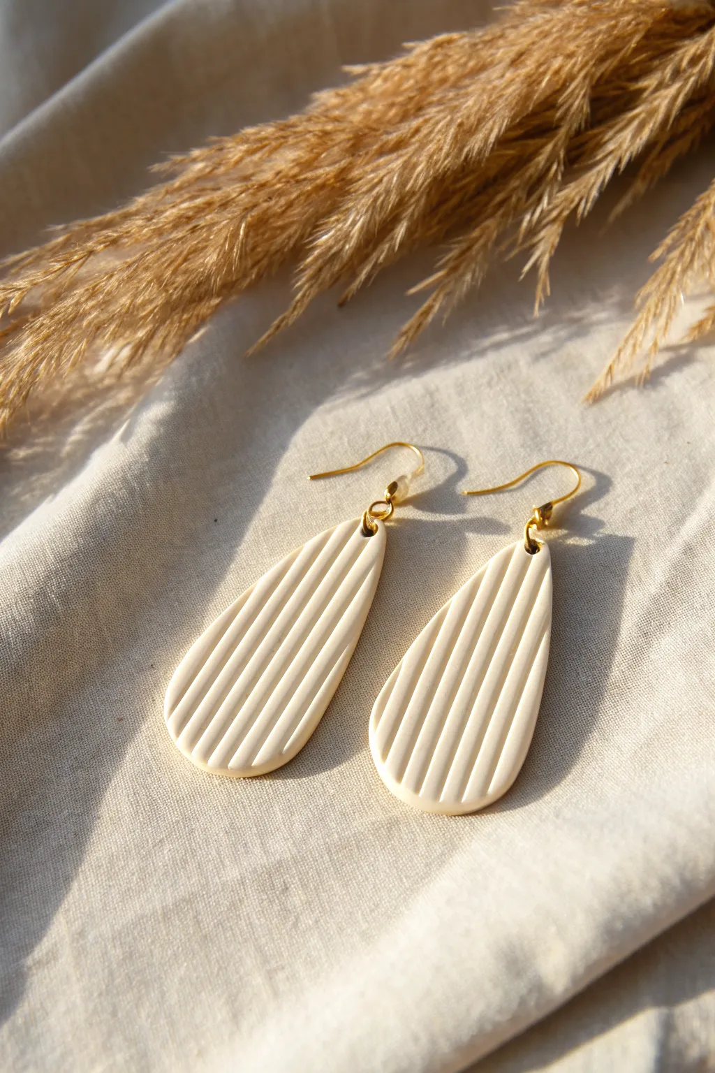 Minimal ribbed clay line earrings in warm off white, side lit to highlight the handmade texture