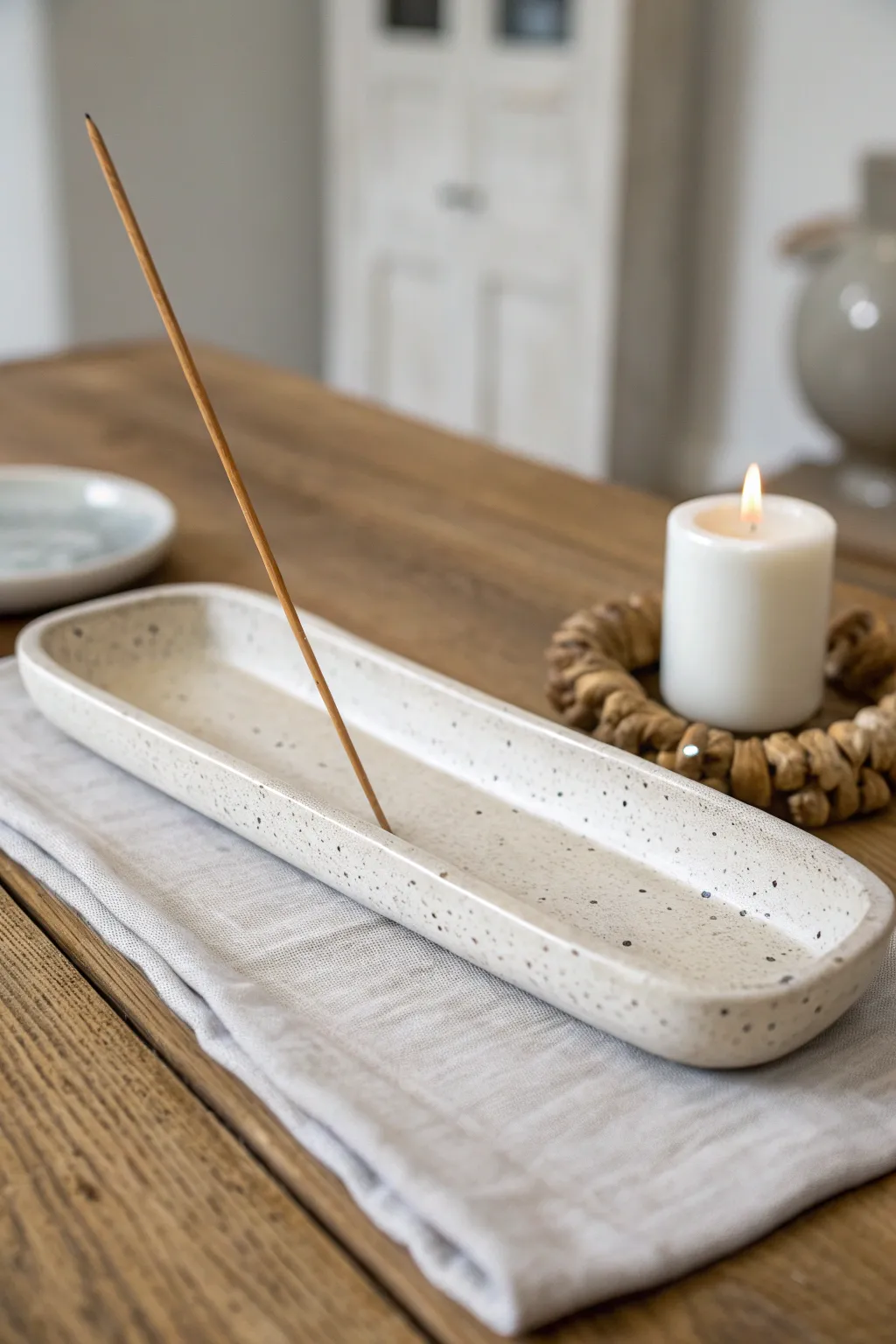 Minimal curved clay incense dish with ash groove, styled softly beside a candle in calm neutrals.