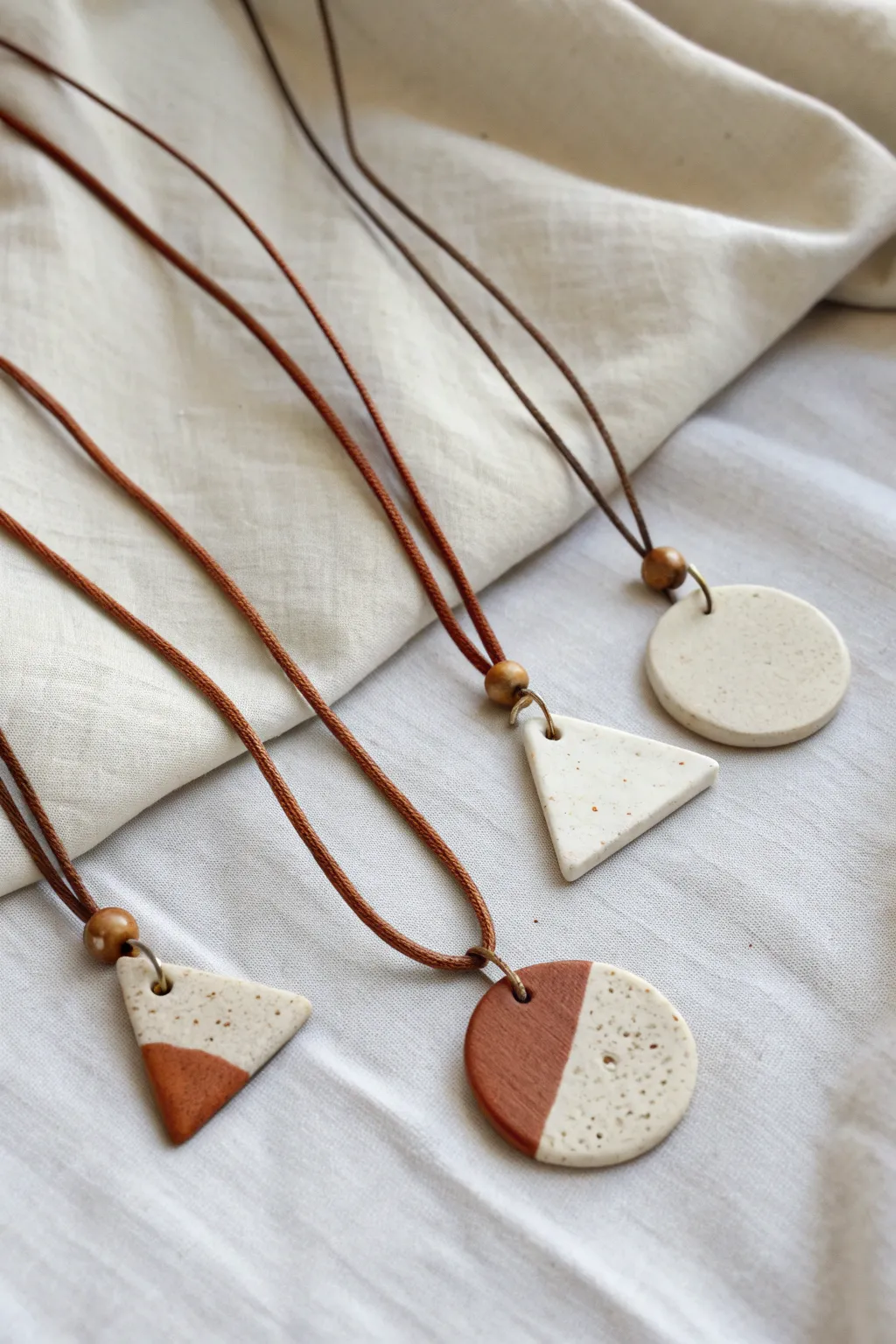 Minimal clay pendant necklaces on cord in soft neutral tones, perfect for easy DIY style.