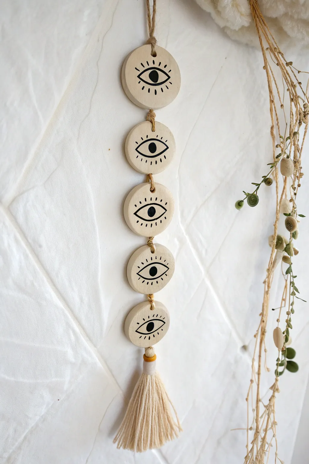 Minimal eye-motif clay talisman wall hanging with brass links and a soft neutral tassel