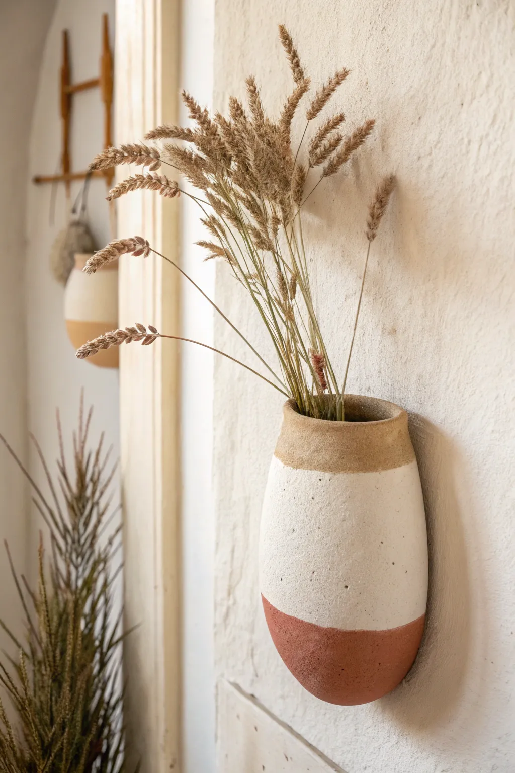 Clean two-tone dip-painted wall pocket with a crisp line, styled with a few airy faux stems.