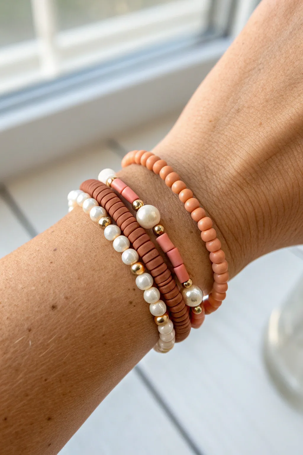 Pearl-and-clay bracelet stack in soft neutrals, highlighting handmade texture with clean contrast.