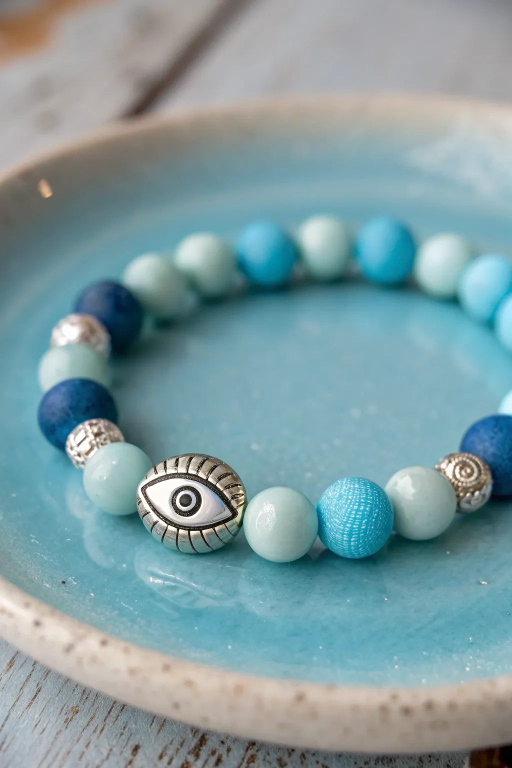 Ocean-blue clay bead bracelet with a protective eye accent and minimalist silver spacers