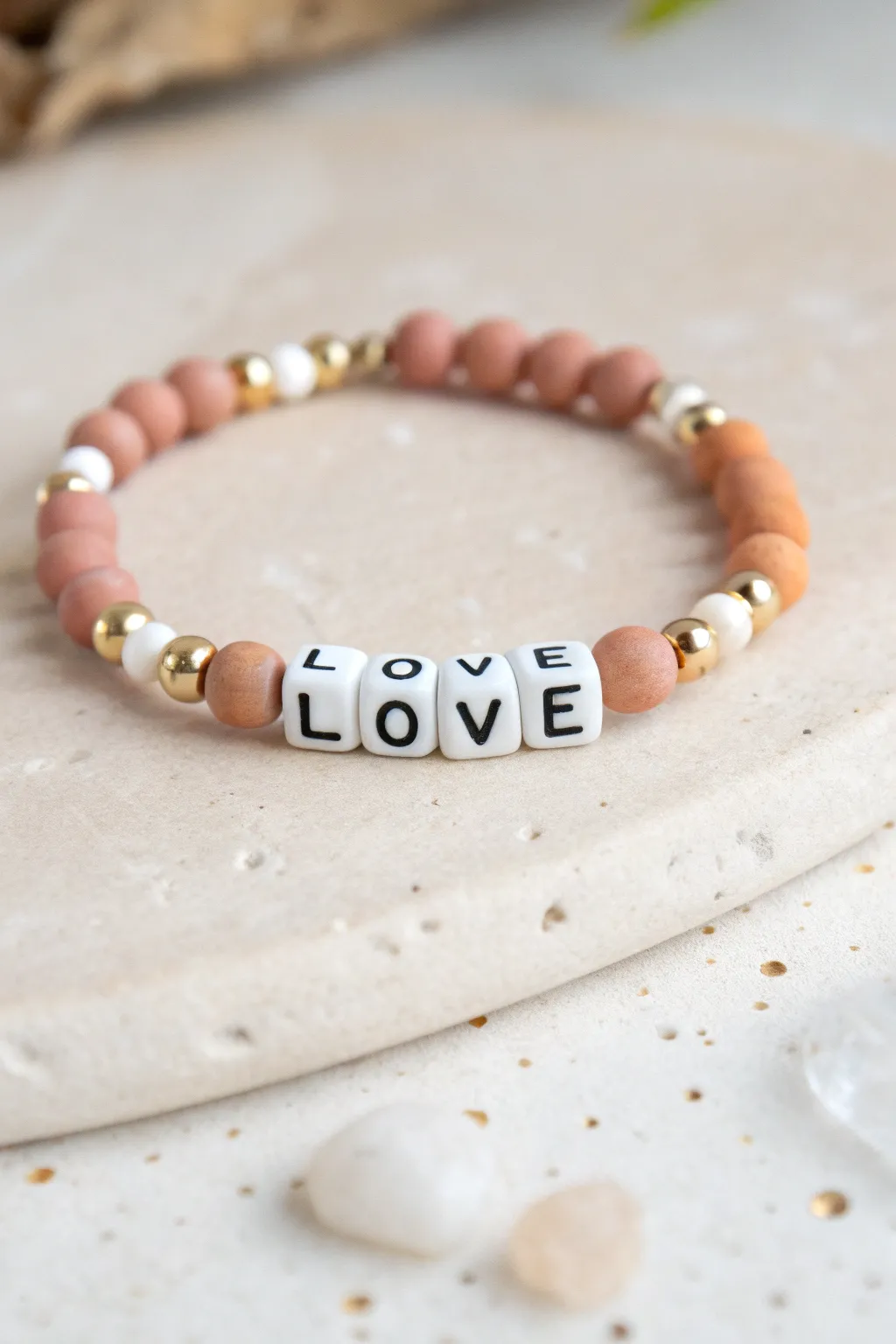 Minimal clay bracelet with centered LOVE letter beads and matching pastel accents.