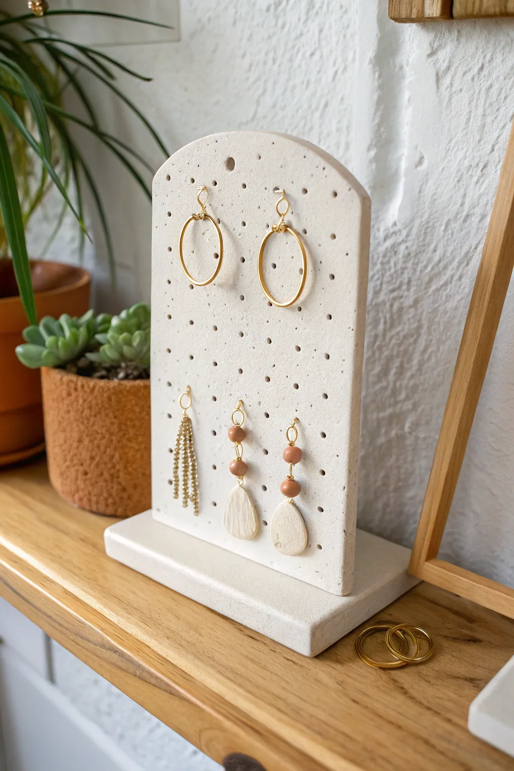 Minimal clay earring display tile with pegs and dotted glaze, sweet and functional decor.