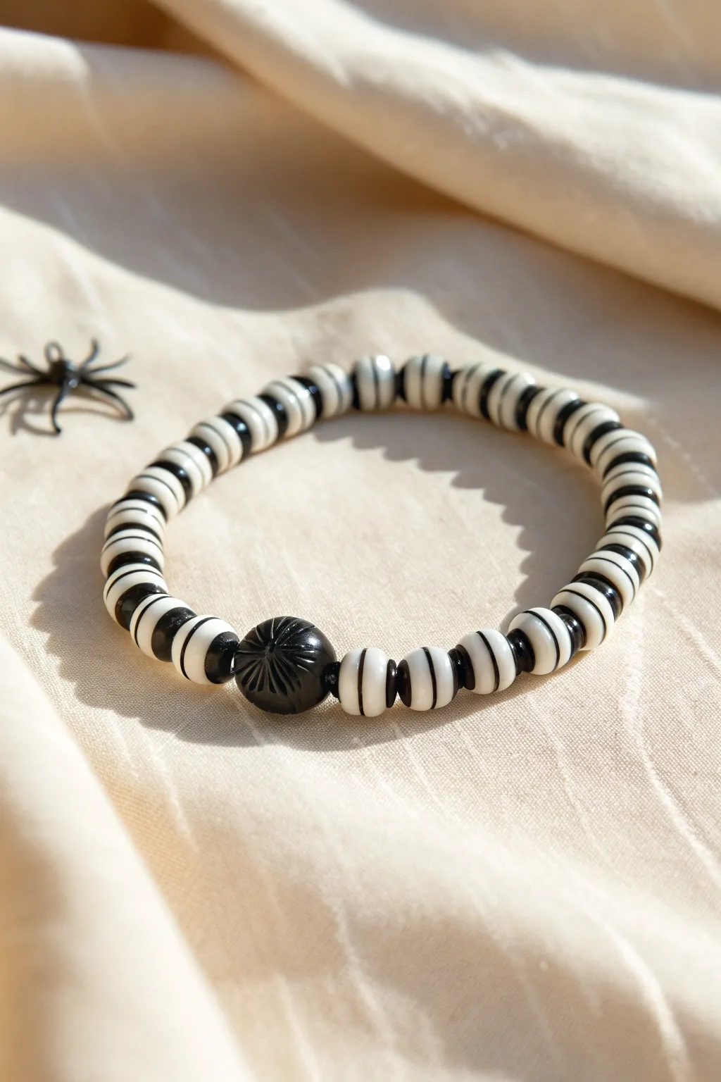 Bold black-and-white heishi stripes with a tiny spider charm for a cute Halloween bracelet