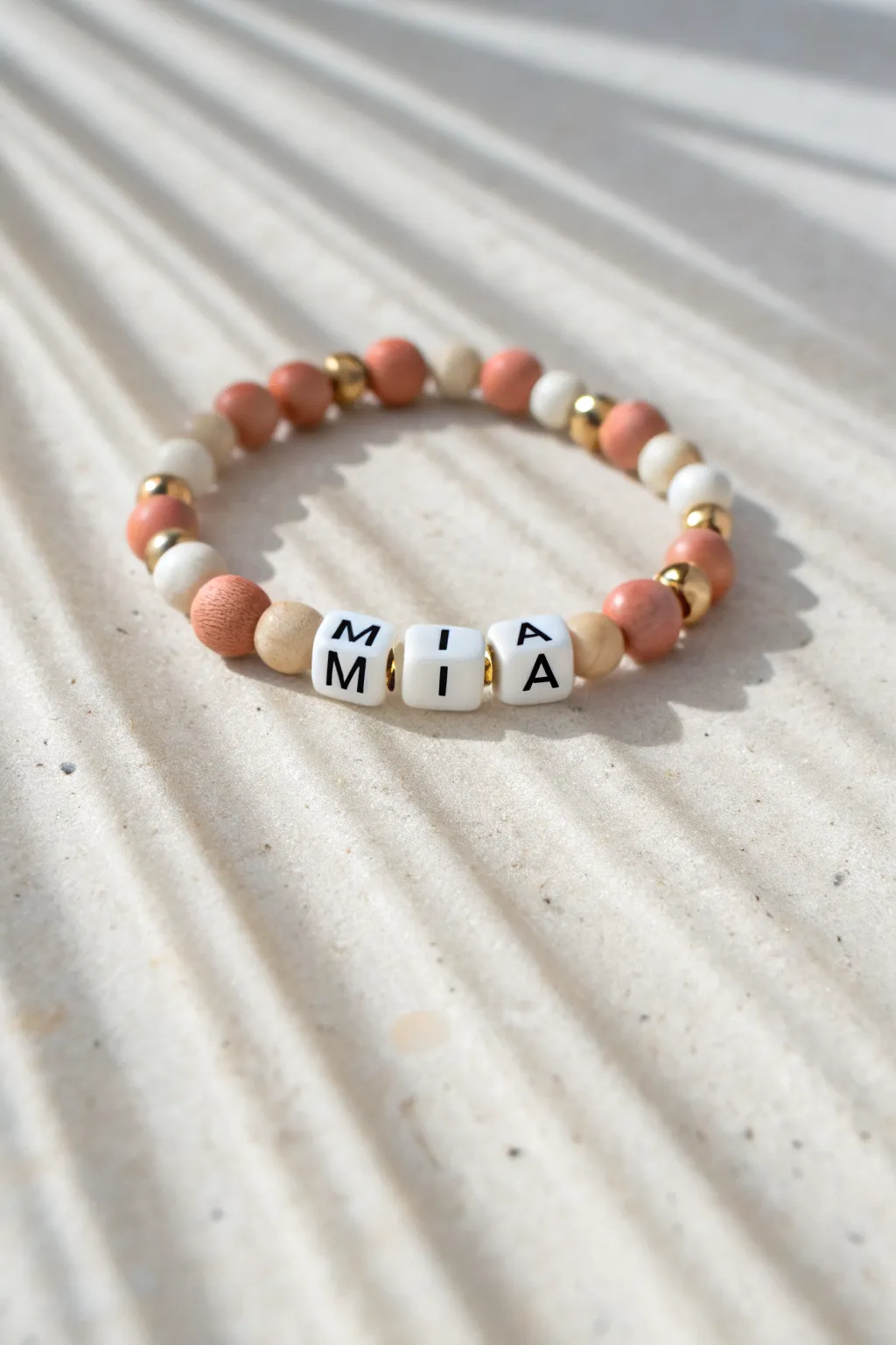 Minimalist boho clay bead name bracelet with letter beads and coordinating heishi beads in warm neutrals.