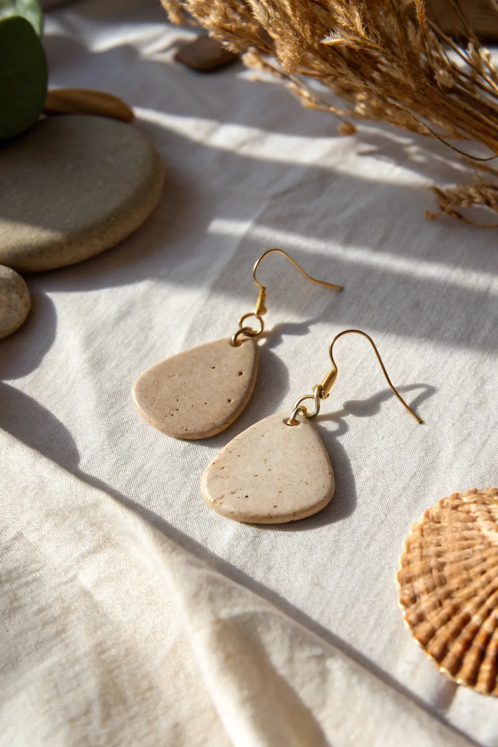Organic blob statement drop earrings in matte stone clay, styled on linen for minimal boho charm.
