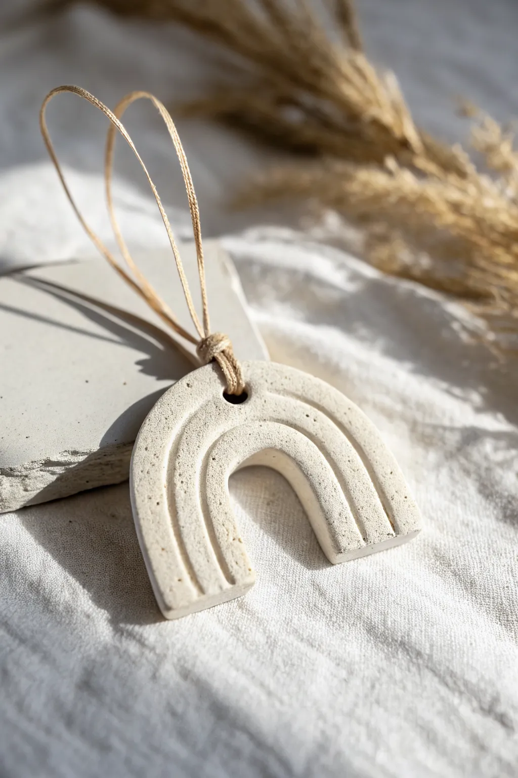 Minimalist clay ornament with geometric cutout, matte neutrals and soft Nordic light.