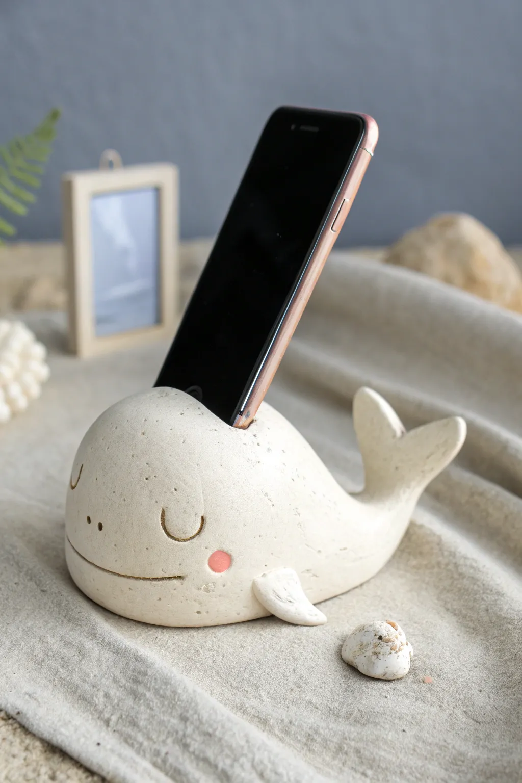 Sleepy whale phone stand in soft blush tones, a cute clay DIY centerpiece for your desk.