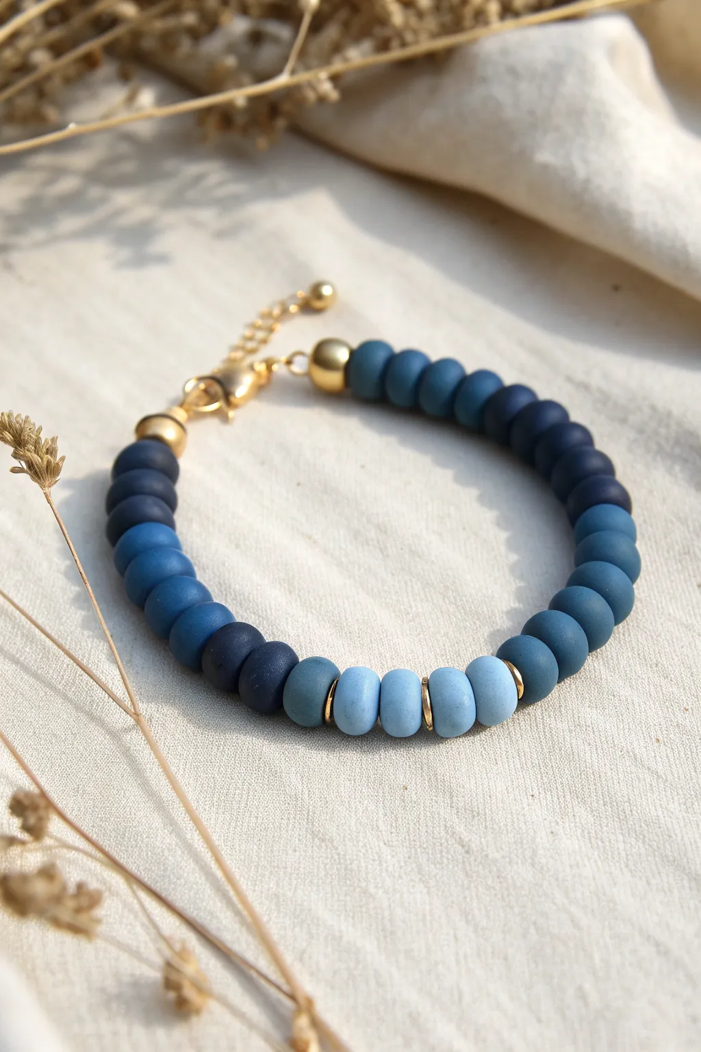 Navy-to-sky ombre clay bead bracelet finished with tiny gold ends on a soft neutral backdrop