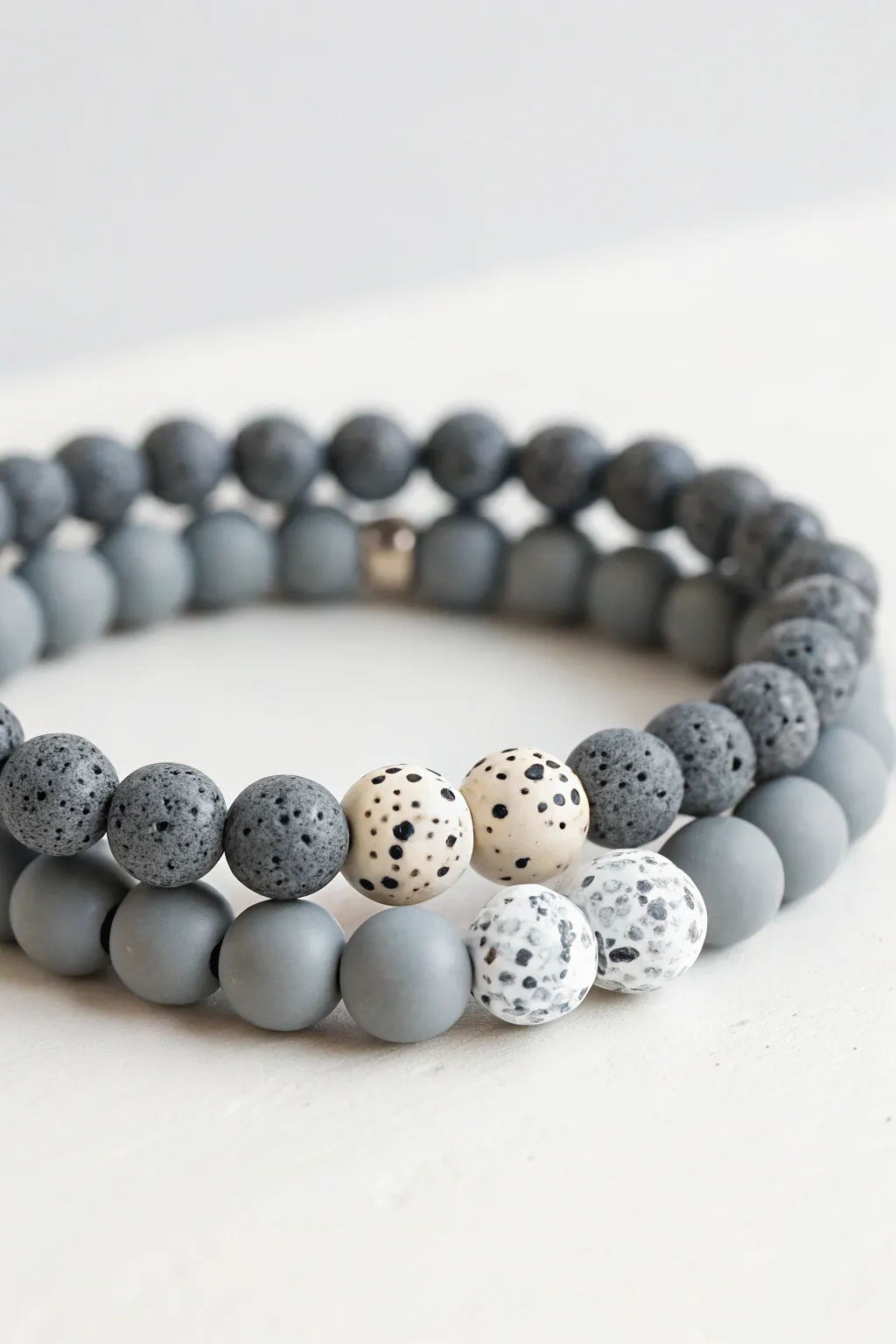 Grey clay beads with terrazzo accents, stacked with a plain bracelet for calm minimalist contrast
