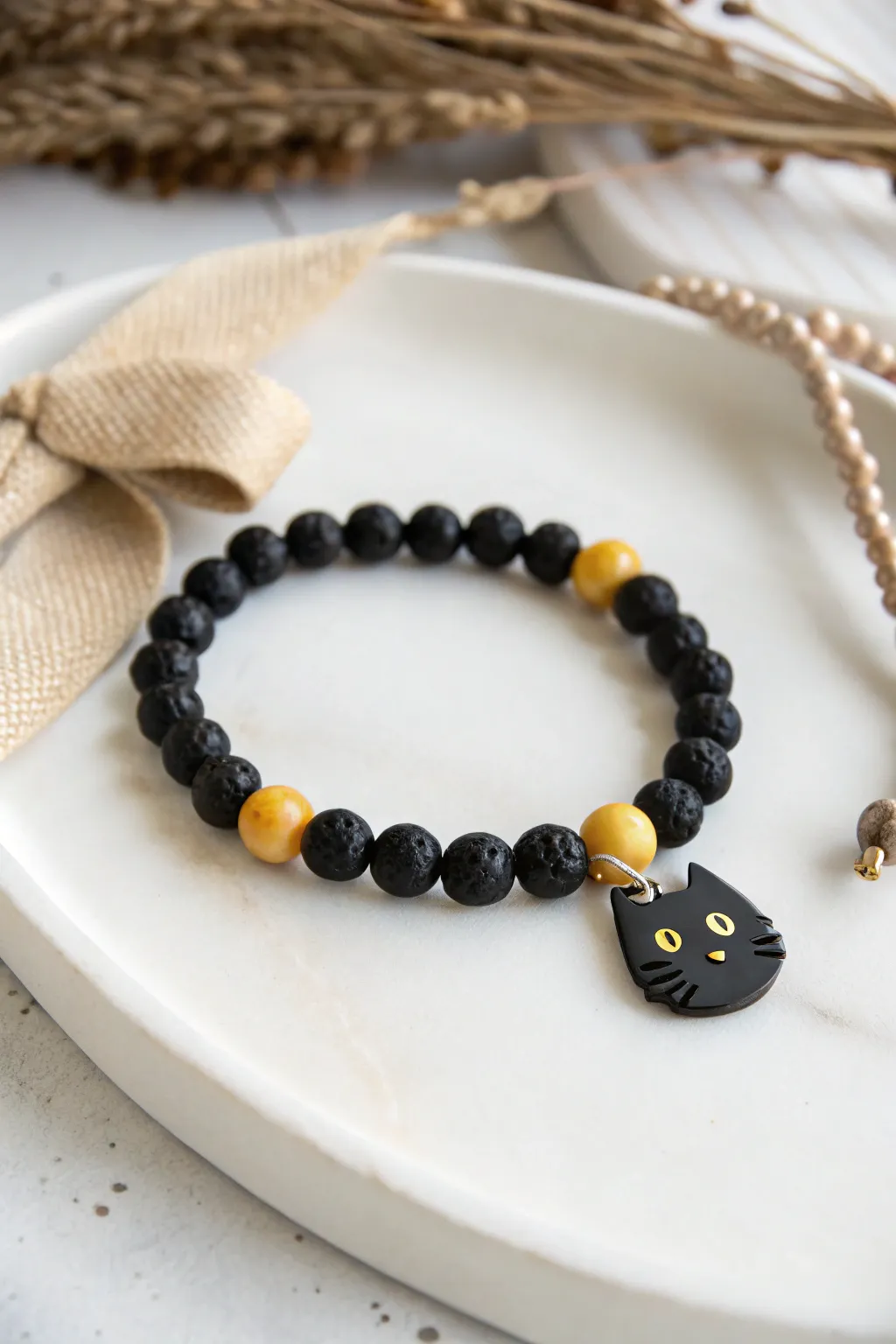 Minimal black clay bead bracelet with a tiny cat charm and bright yellow eyes for Halloween