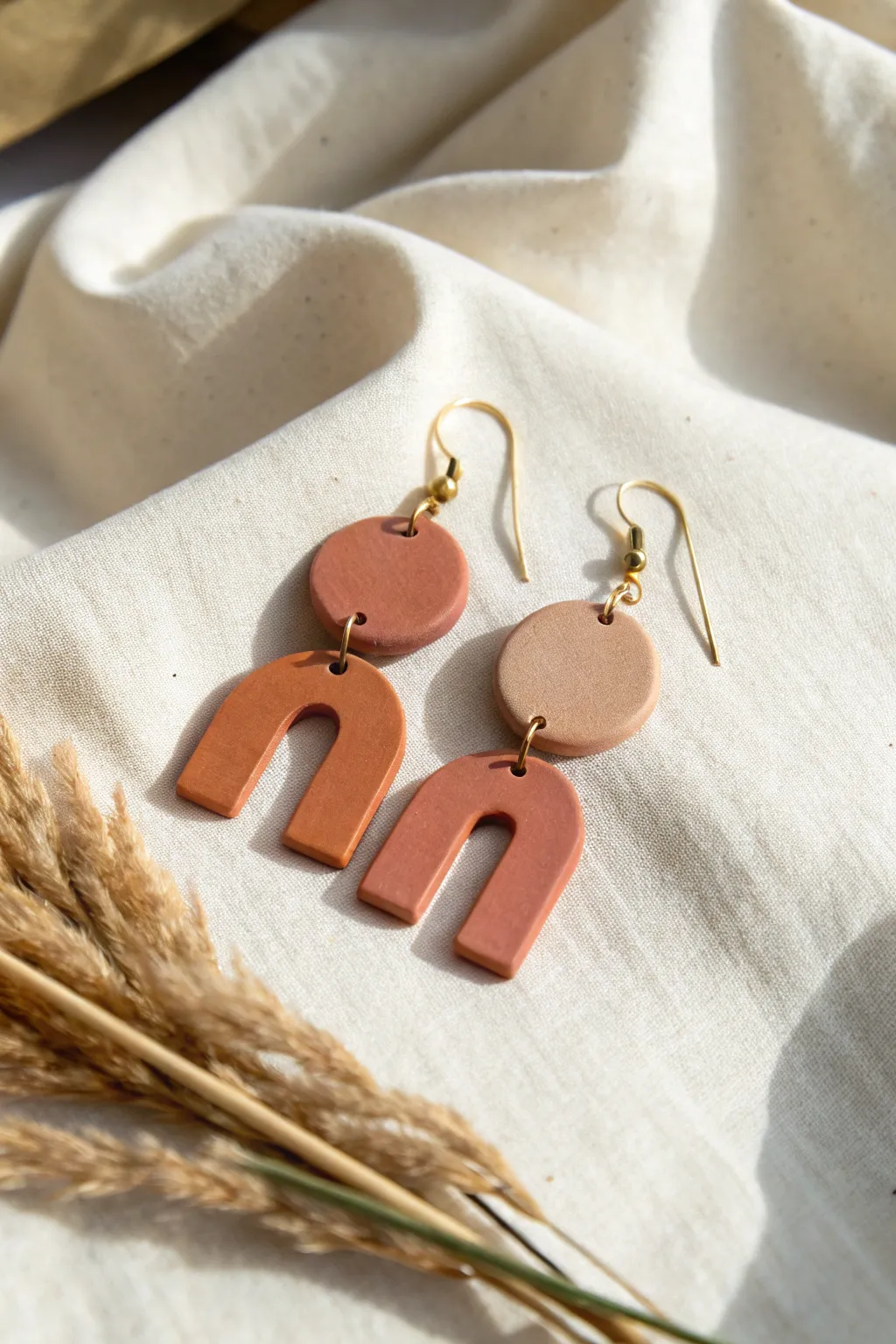 Neutral geometric clay earrings on linen, minimalist Scandinavian style with a soft boho touch.