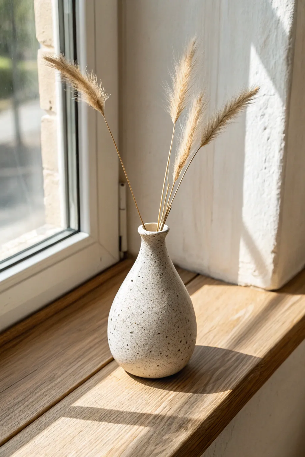 Petite paper clay bud vase with dried stems, a calm minimalist touch for sunny shelves.