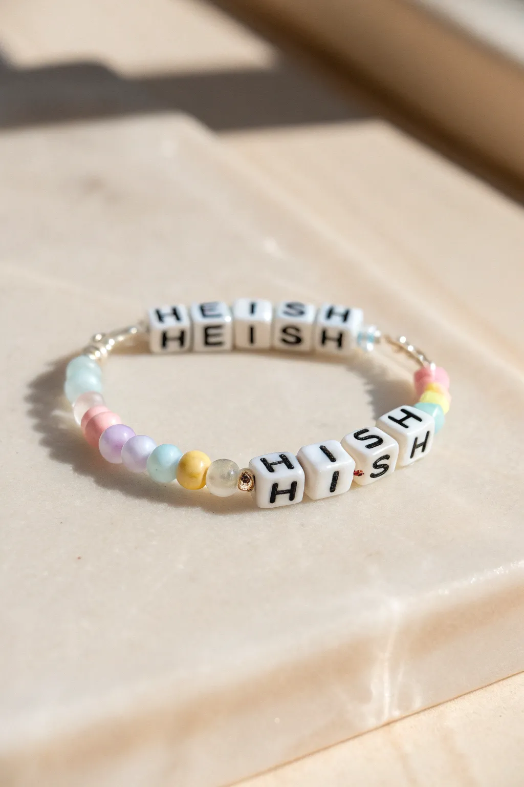 Pastel heishi bracelet with a simple letter-bead centerpiece, minimalist and softly boho.