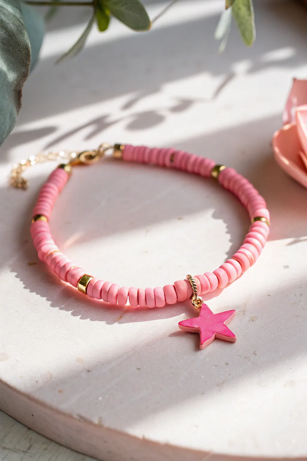 Bright pink heishi bracelet with an off-center star and spaced gold shine spacers