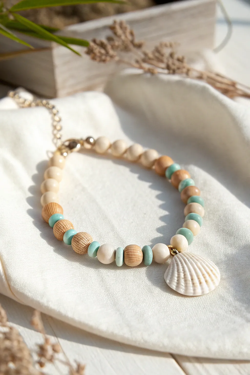 Coastal neutral polymer clay bracelet with shell accent and soft aqua heishi beads on linen