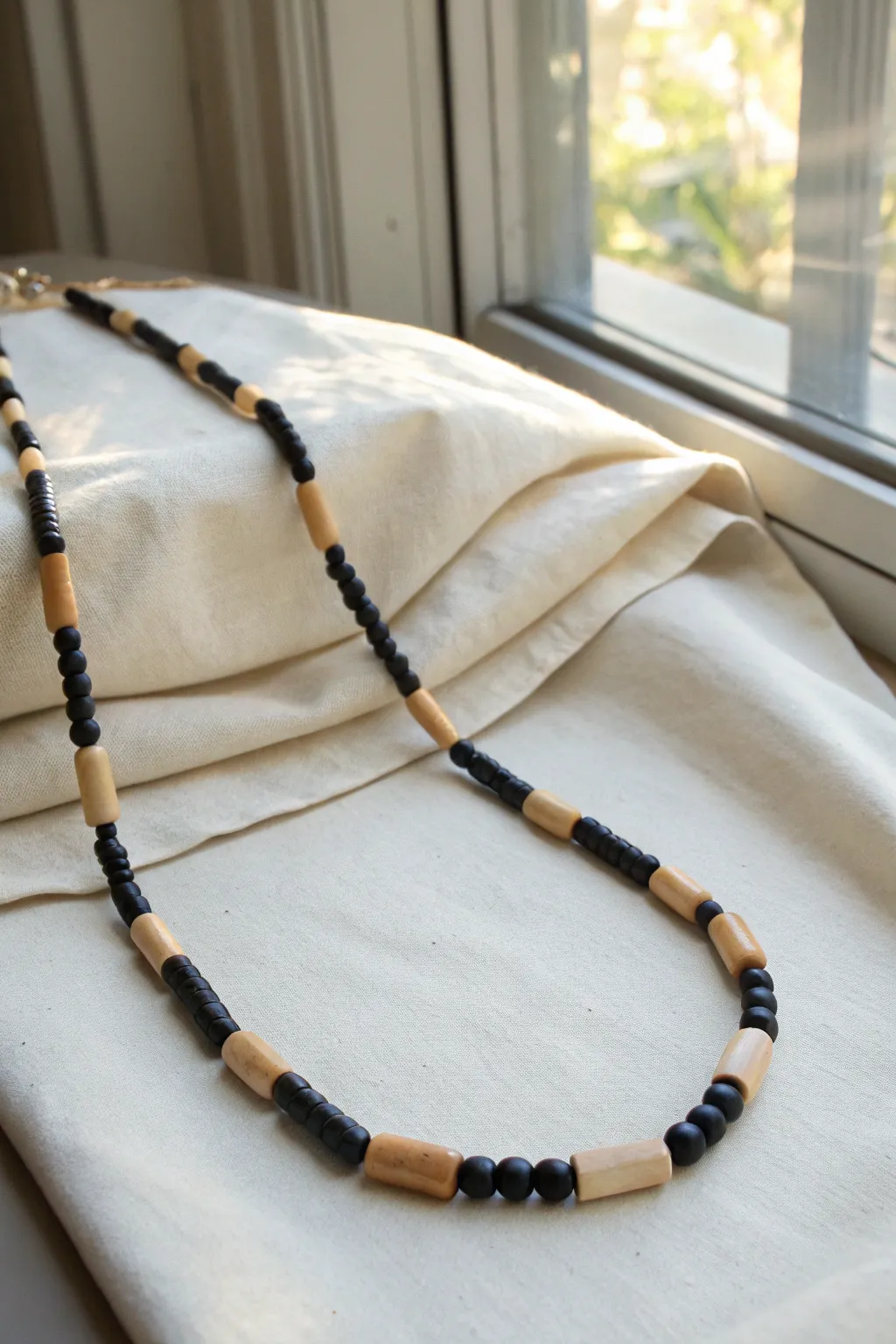 Minimal black and cream polymer clay necklace with tube and bar beads, styled clean and modern.