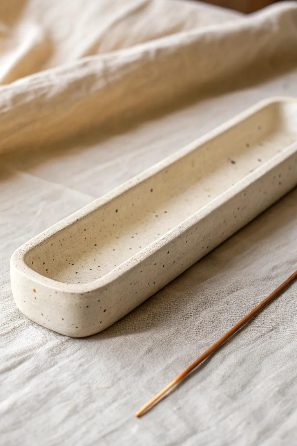 Minimal curved-channel ceramic incense holder with a tiny catch bowl, calm and sculptural