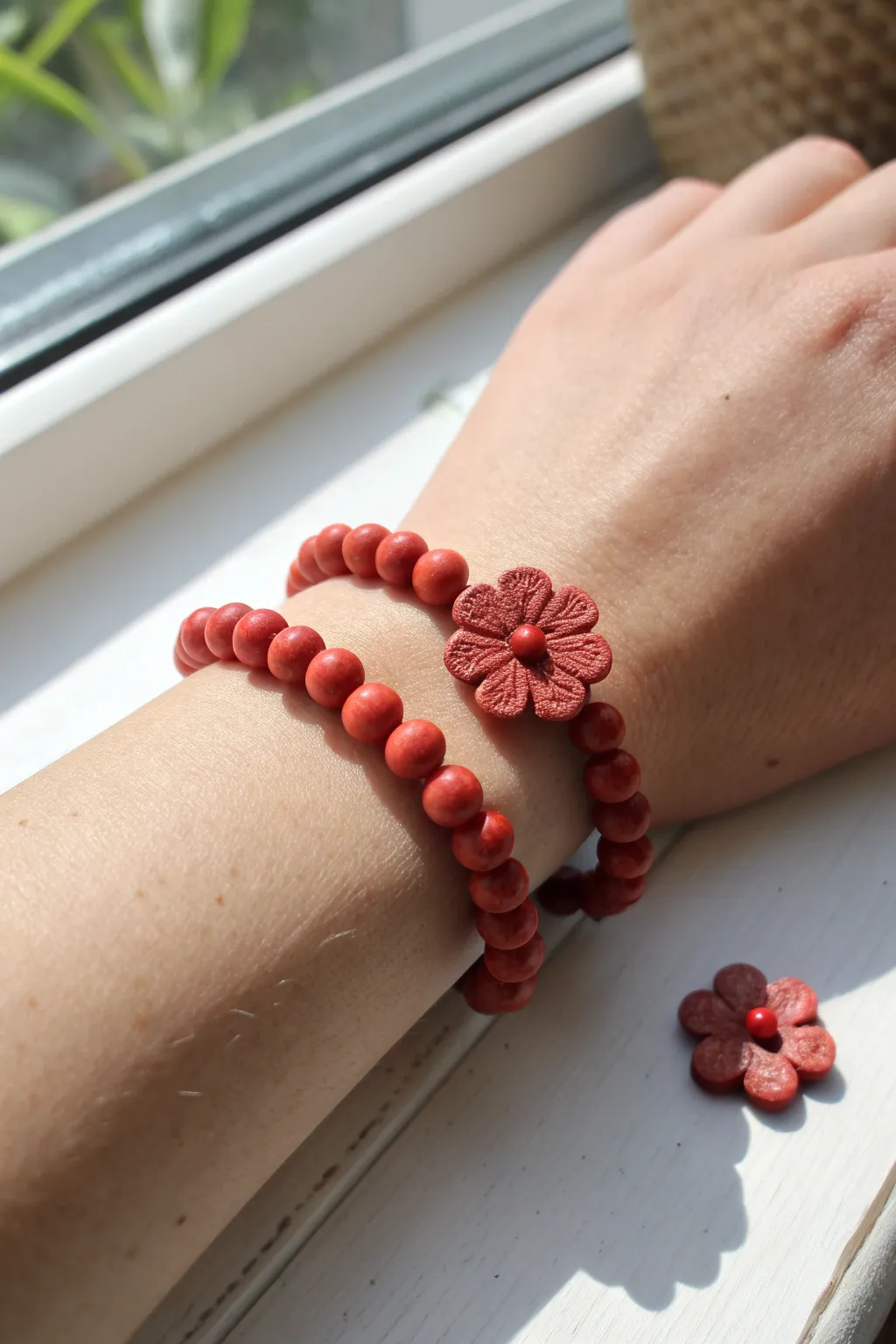 Red clay beads with a delicate flower accent, styled as a simple two-bracelet mini stack.