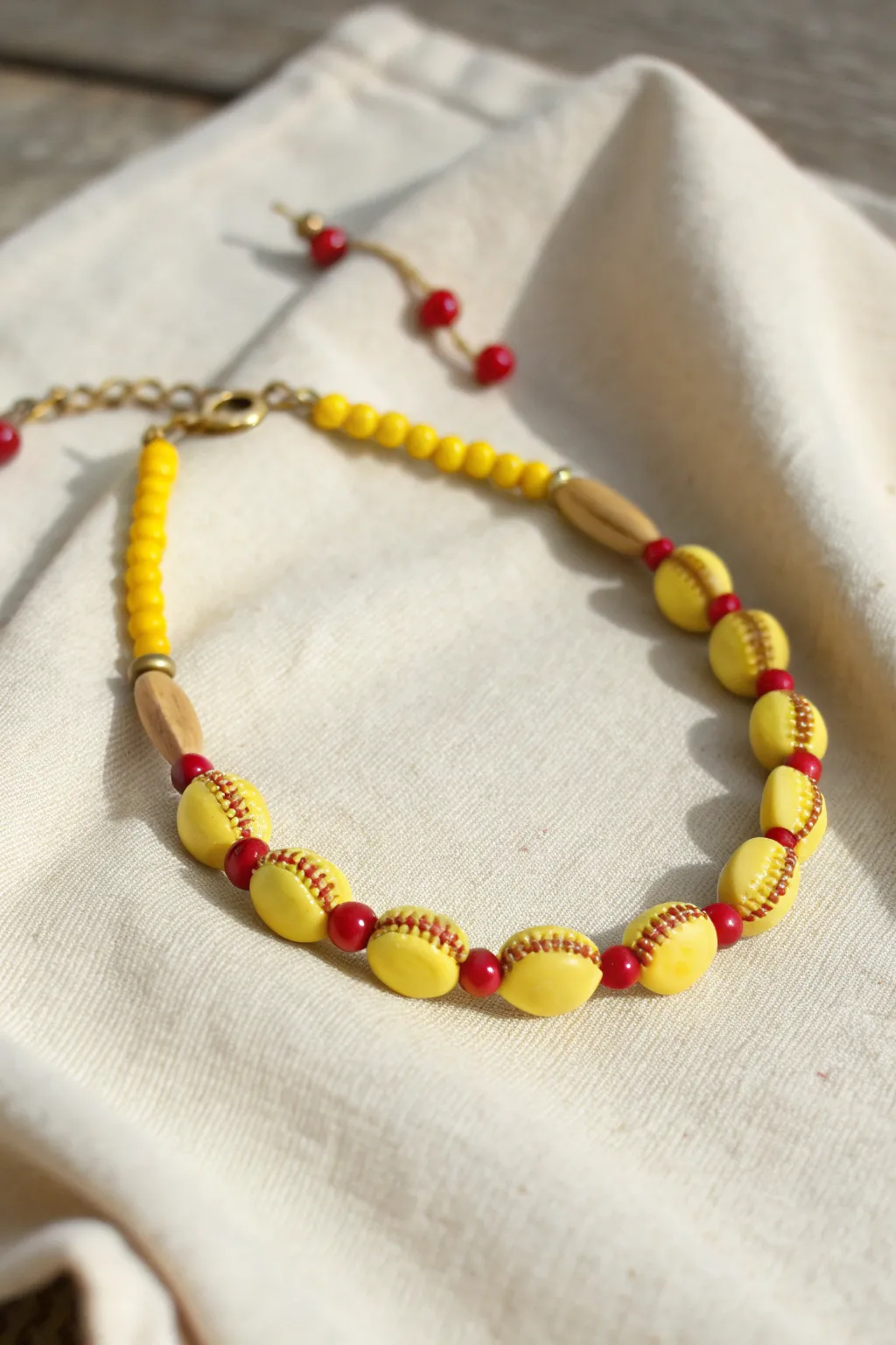 Minimal softball inspired clay bead bracelet with red stitch blocks on warm neutral linen.
