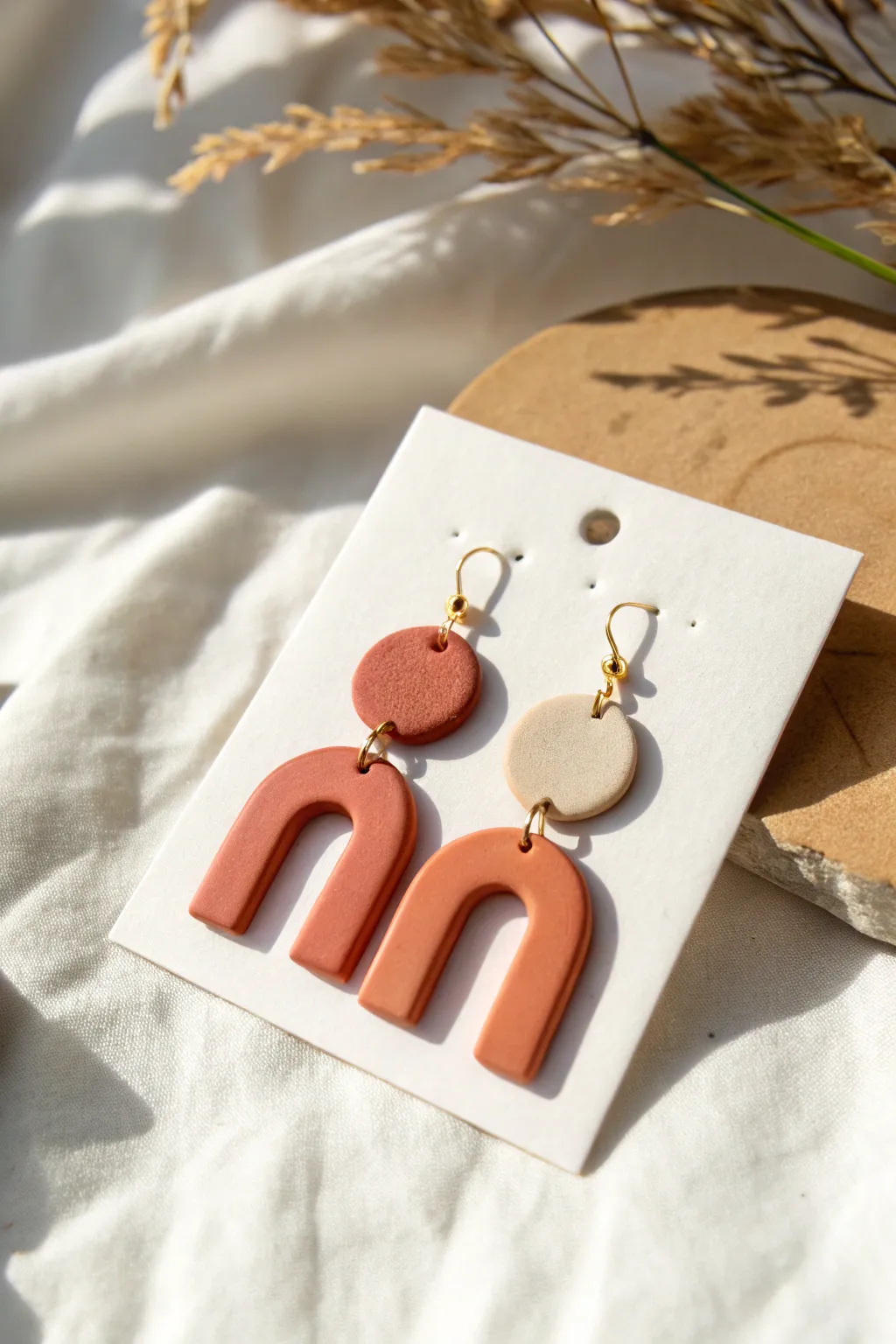 Bold polymer clay statement earrings in minimalist arches and circles, styled Scandinavian-boho.