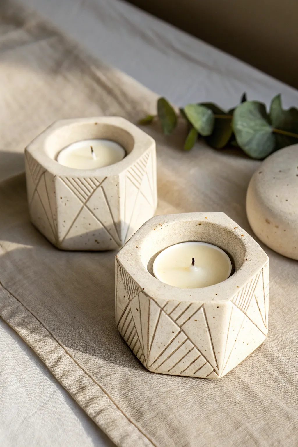 Minimal geometric clay tea light holders with carved lines, soft light and cozy neutral tones.
