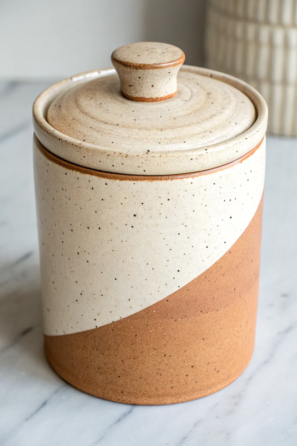 Two-tone ceramic jar with raw clay base and matte glaze top for a clean earthy contrast.