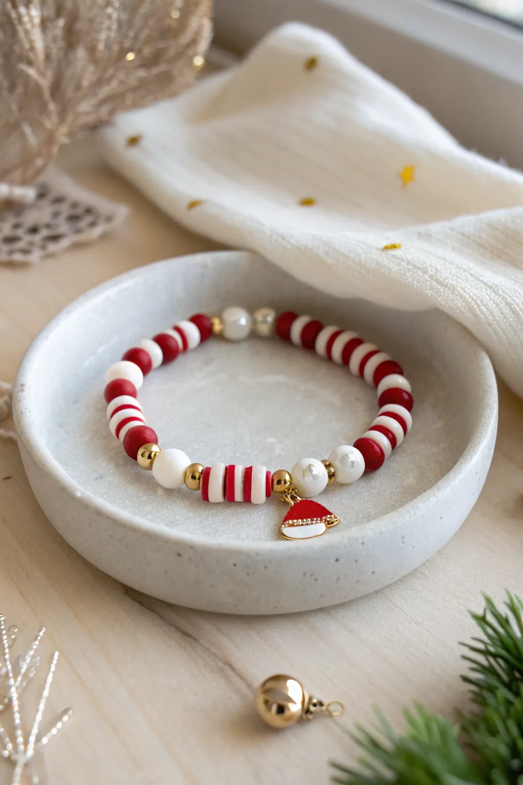 Festive red and white clay bead bracelet with Santa hat charm and gold accents, minimalist joy.