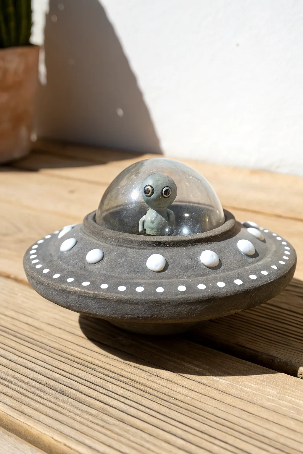 Cute mini clay UFO with tiny alien pilot, minimalist sci-fi charm for your pottery shelf.