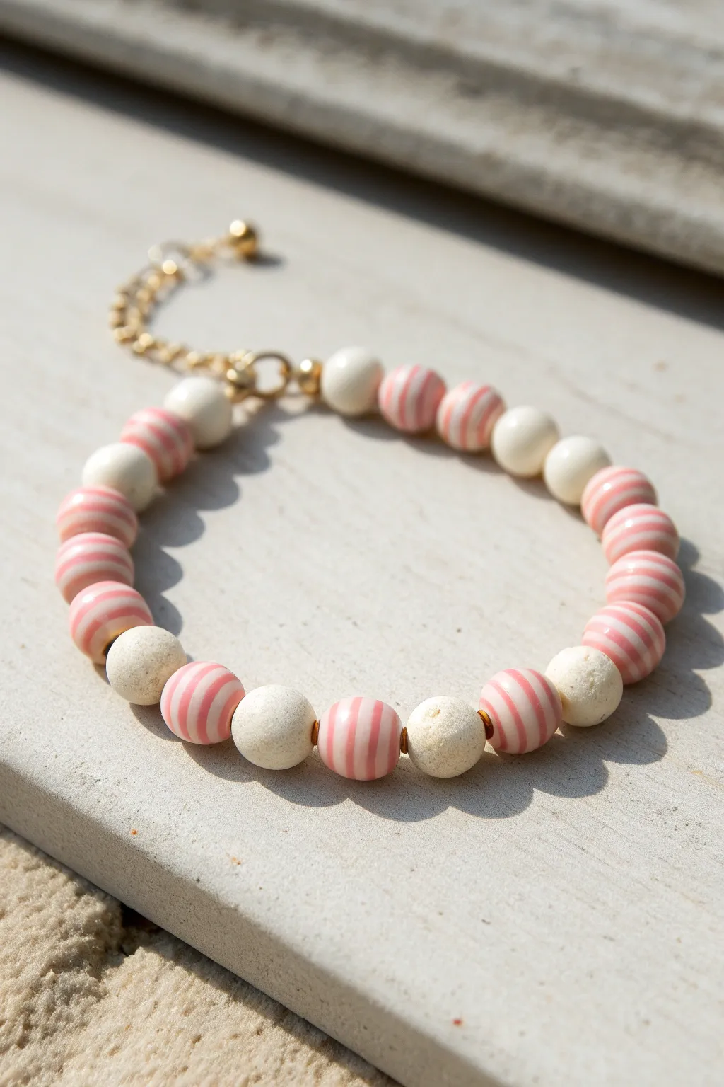 Candy stripe clay bead bracelet in blush and white, simple repeat pattern with Nordic calm.