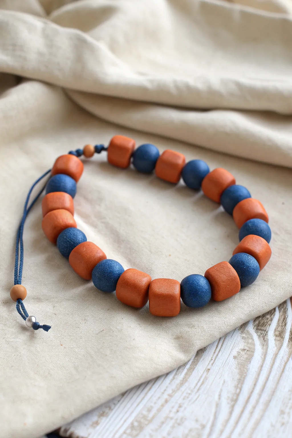 Complementary clay bead bracelet in crisp repeats, a bold pop against soft neutral linens.